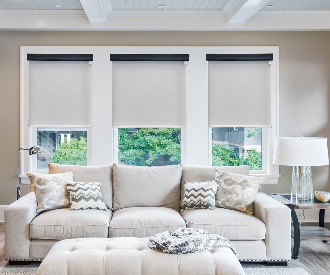 Living room with motorized roller shades installed on three windows